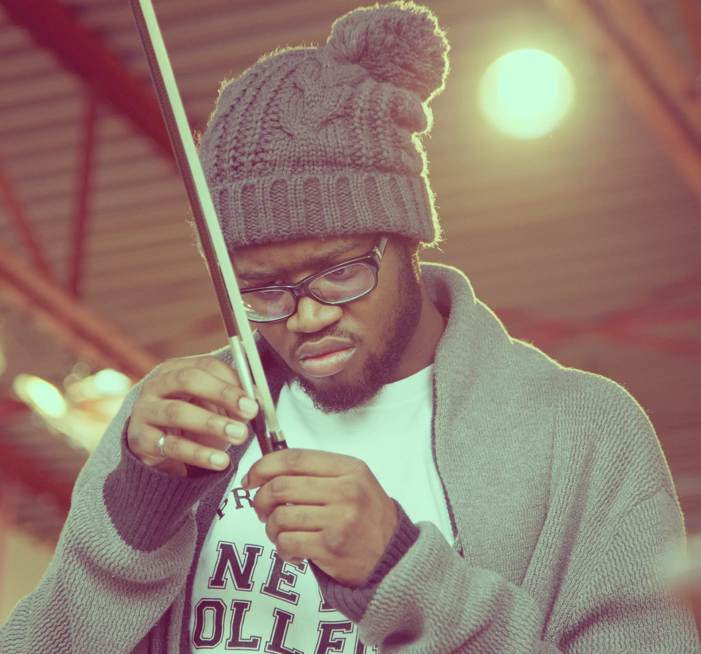 Andrew Forde inspecting his violin bow in a studio.